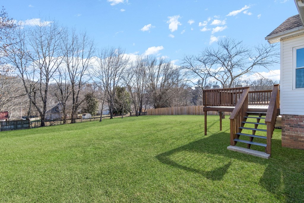 the back yard of a house with a wooden deck and a staircase in the grass