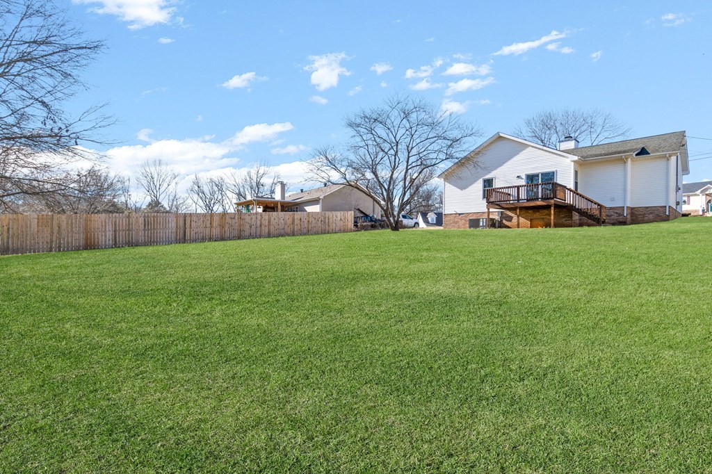 a yard with a fence and a house in the background