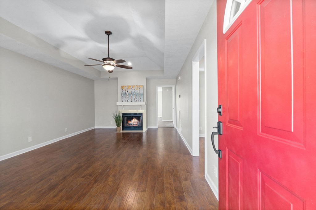 an empty living room with a red door and a fireplace