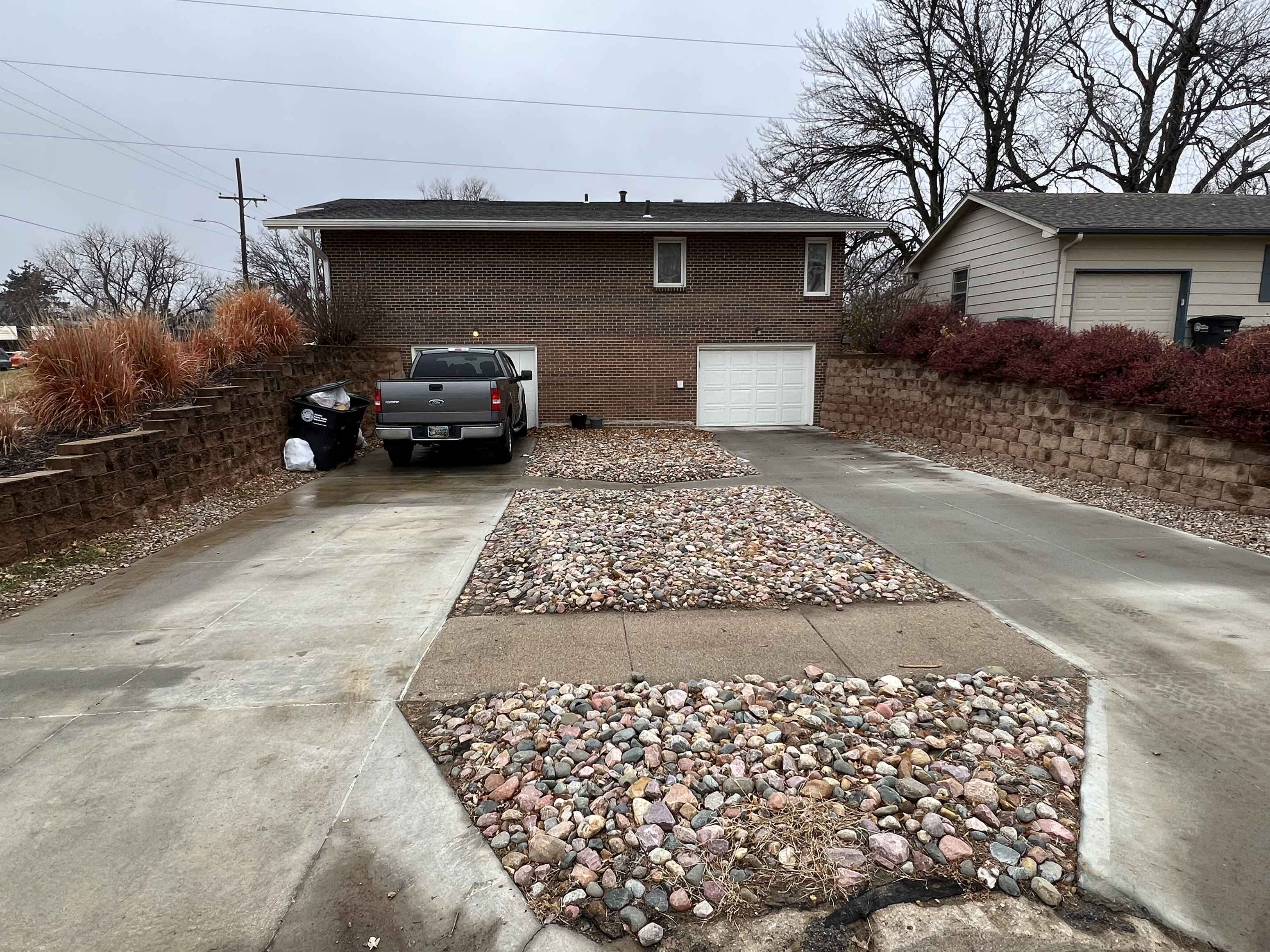 a driveway with rocks and gravel in front of a house