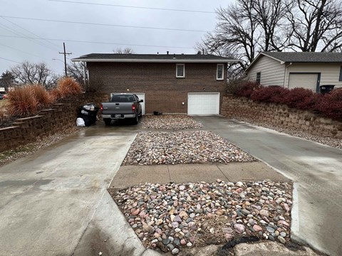 a driveway with rocks and gravel in front of a house