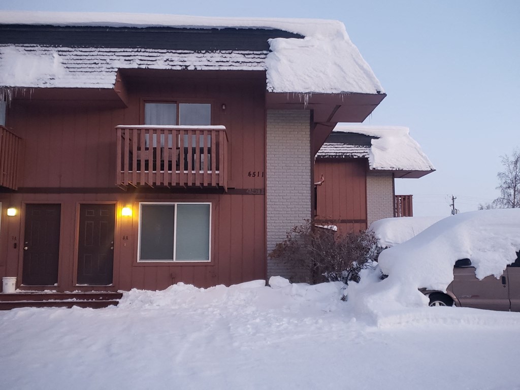 A house with a brown exterior is covered in snow.
