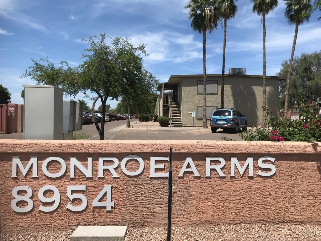 A sign that says Monroe Arms 8954 in front of a building.