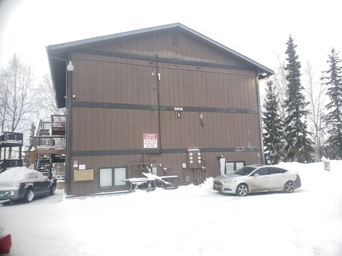 a brown barn with cars parked in front of it