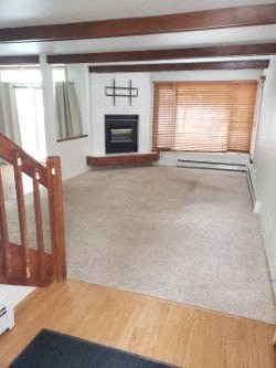 A living room with a fireplace and a rug on the floor.