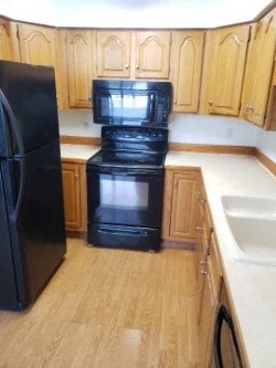 A black refrigerator stands next to a black oven in a kitchen.