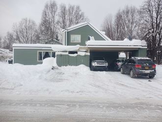 a green house with cars parked in the snow