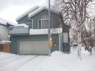 a green house with a garage in the snow