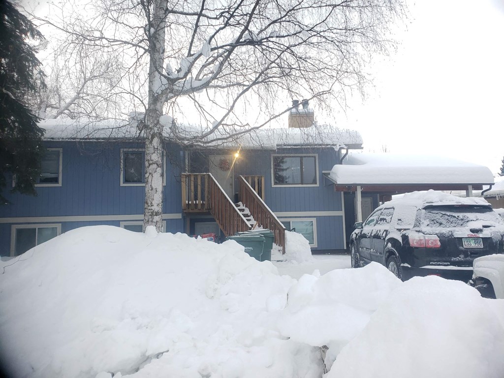 a blue house with snow piled up in front of it