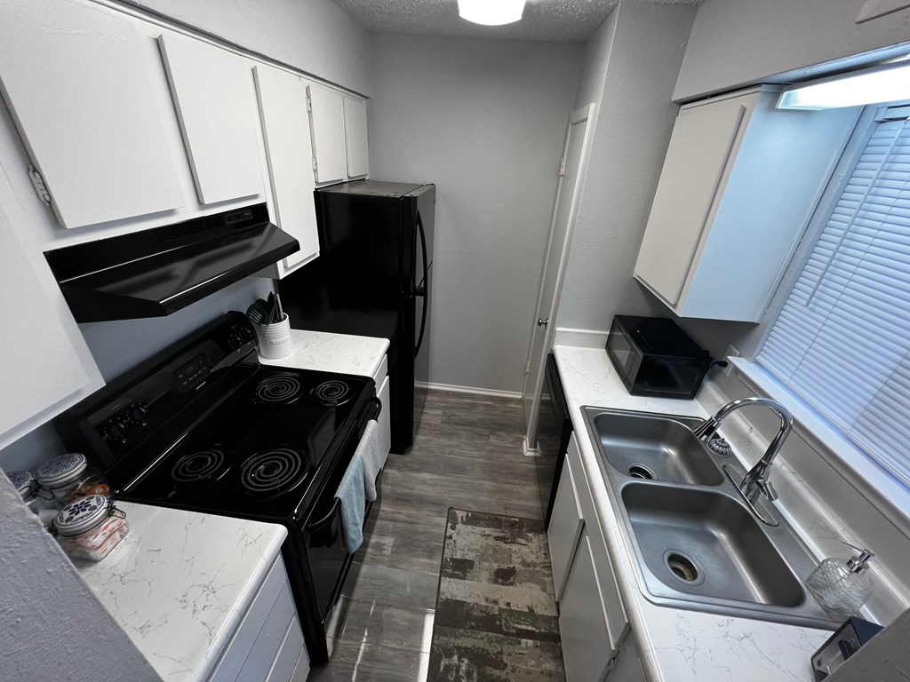 a small kitchen with white cabinets and a black stove