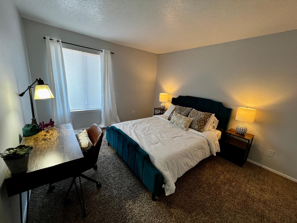 a bedroom with a bed and a desk and a window