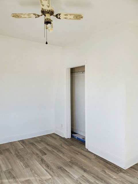 a room with white walls and a closet and a ceiling fan