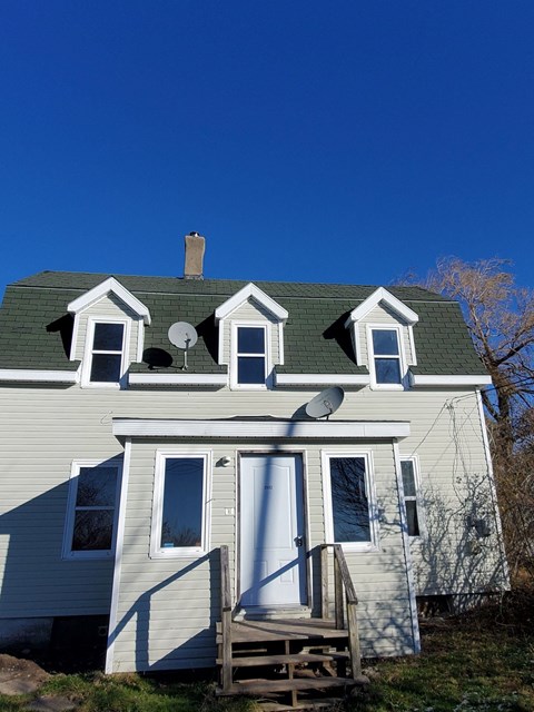 a white house with a green roof and white windows