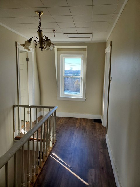 a hallway with a staircase and a window and a wooden floor