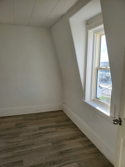 a small room with a window and wooden floors