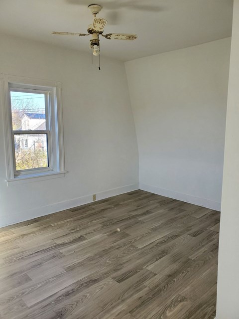 a room with wooden floors and a window and a ceiling fan