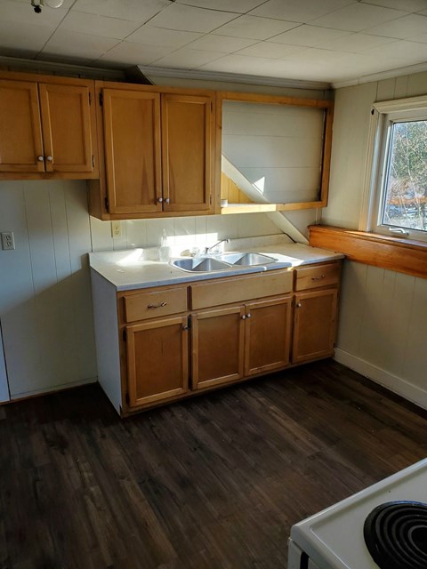 a kitchen with a sink and wooden floors