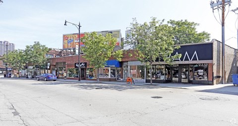 a street view of a city street with shops and trees