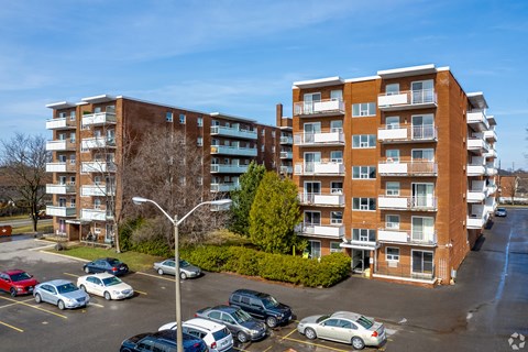 A parking lot with cars and two apartment buildings.