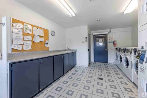 A laundromat with washers and dryers and a bulletin board on the wall.
