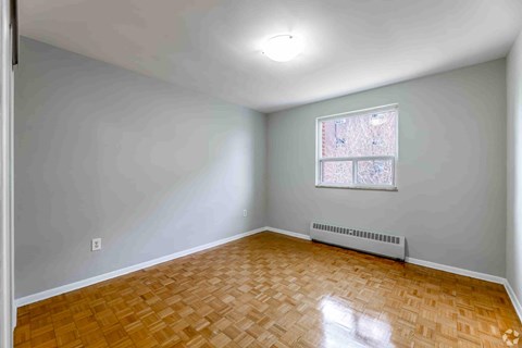 A room with a window and a radiator on the floor.