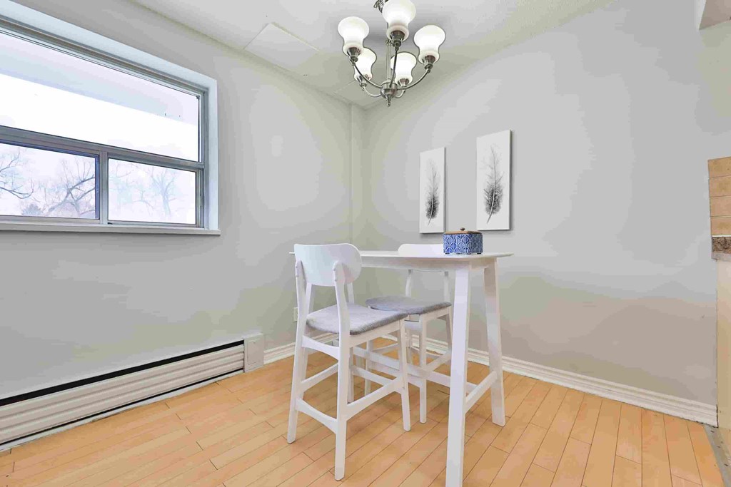 A white chair and table in a room with a window.