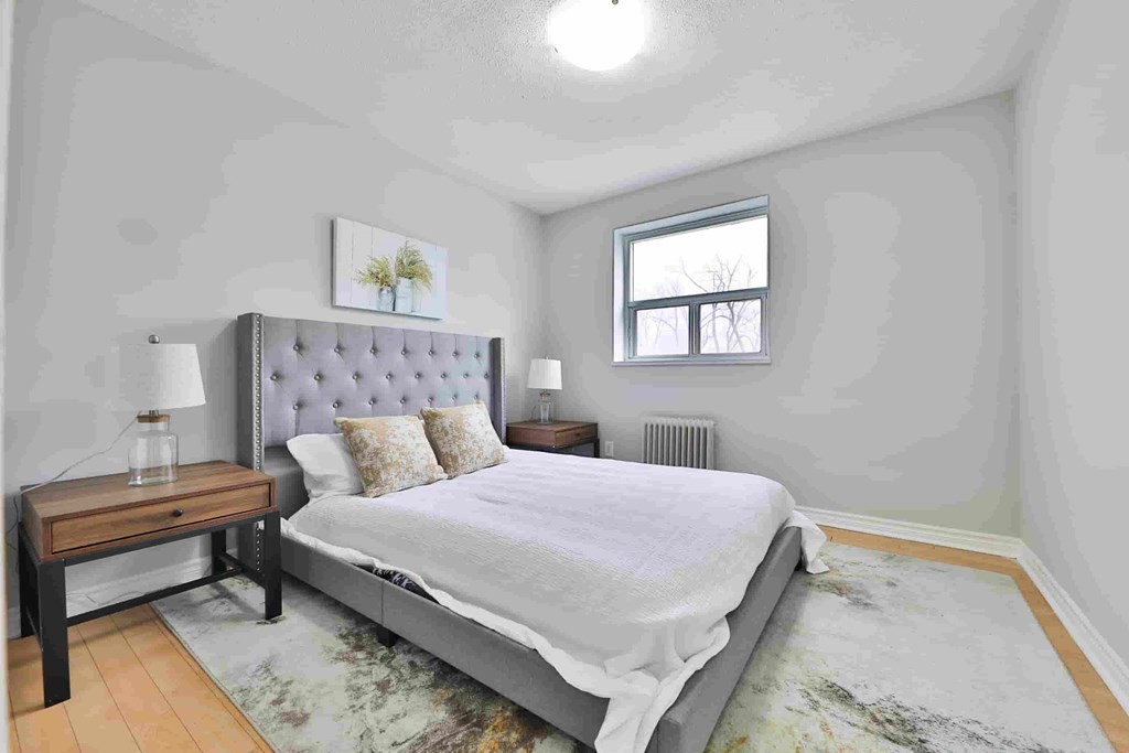 A bedroom with a large bed and a small table with a lamp on it.