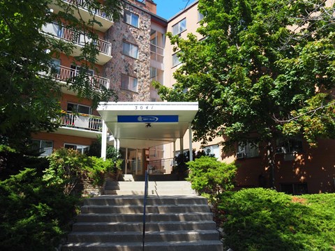 A building with a blue sign that says "3041" is surrounded by trees and bushes.