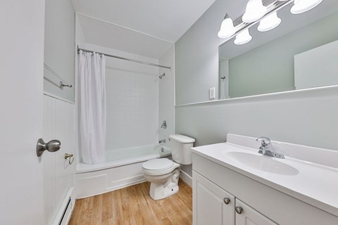 A white bathroom with a toilet, sink, and shower.