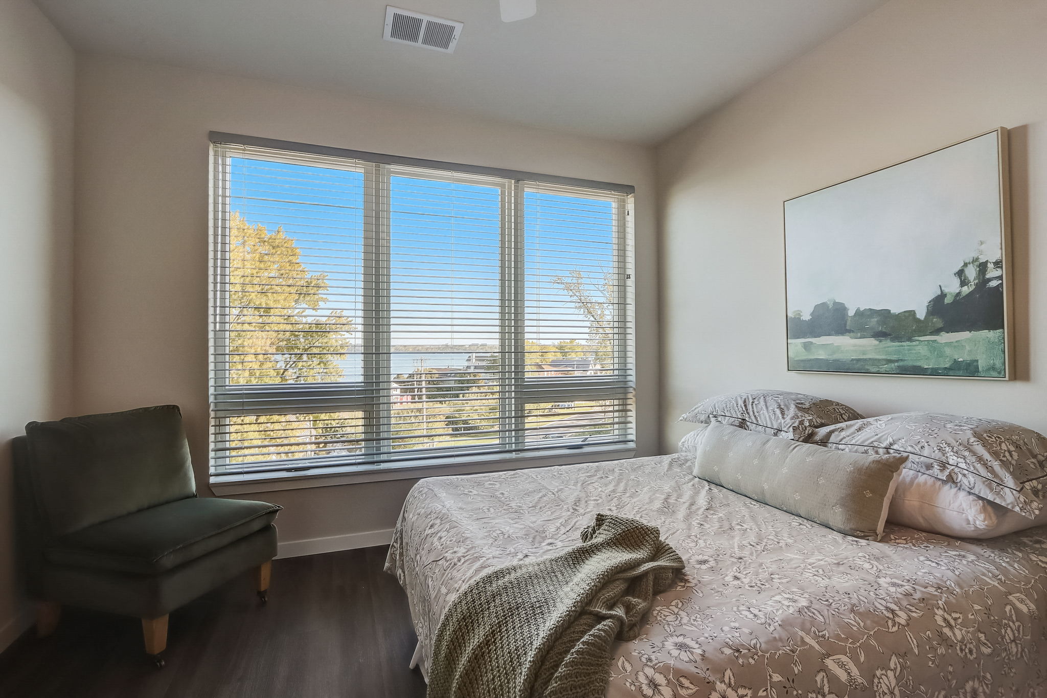 the master bedroom has a large window and a bed with pillows
