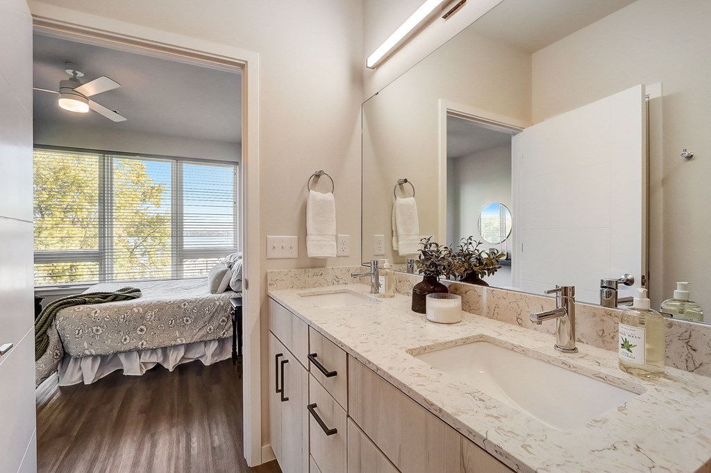 a bathroom with a sink and a mirror and a bedroom with a bed