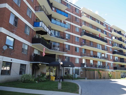 A red brick apartment building with balconies and a flag.