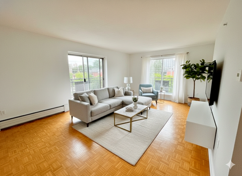 A living room with a grey couch, a white coffee table, and a wooden floor.