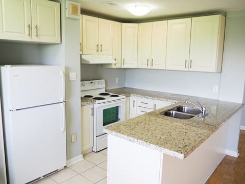 A kitchen with a white refrigerator and a granite counter top.