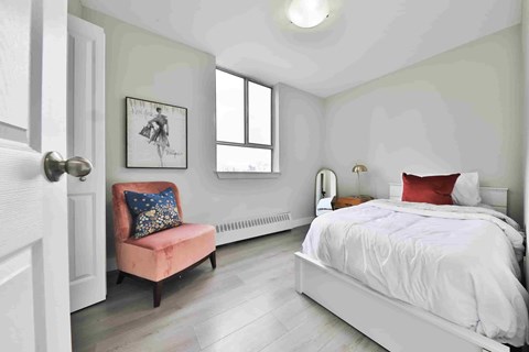 A bedroom with a white bed and a pink chair.