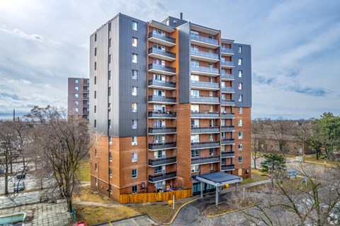 A tall apartment building with a parking lot in front.