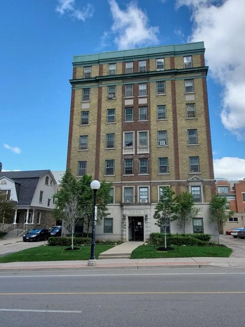 A tall building with a green roof stands on a street corner.