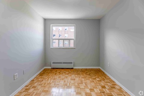 A room with a window and a radiator on the floor.