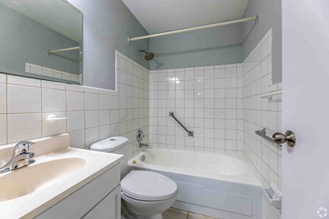A white toilet sits next to a white bathtub in a bathroom.