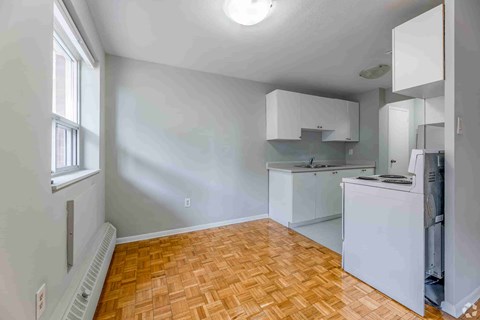 A kitchen with white cabinets and a wooden floor.