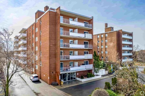 A large red brick apartment building with a car parked in front.