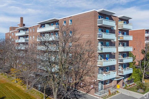 A large apartment building with a red brick exterior and multiple balconies.