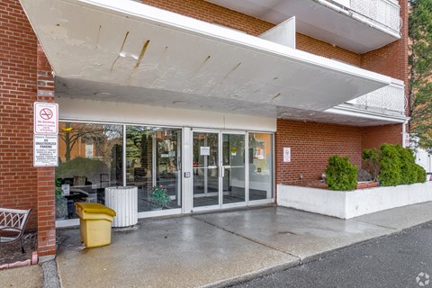 A no parking sign is on a pole in front of a building.