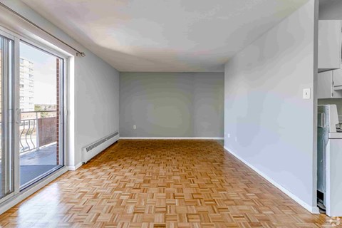 A room with a wooden floor and a window overlooking a balcony.