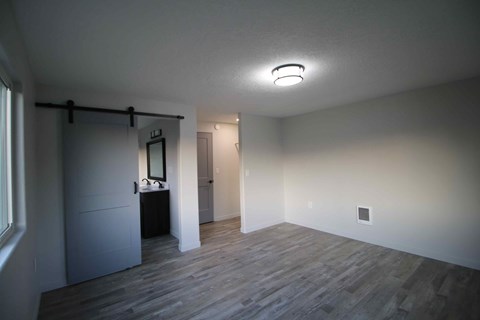 a living room with a wood floor and a door to a bathroom