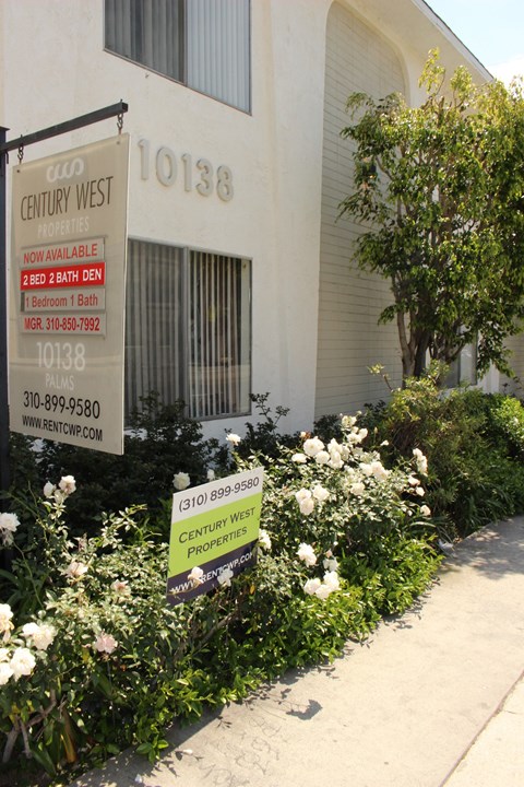 the front of a building with a sign and flowers