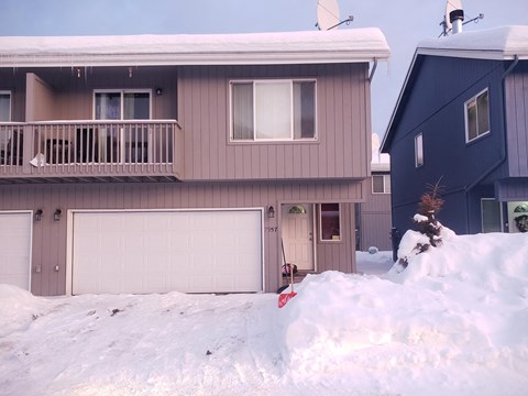 A house with a garage and a balcony covered in snow.