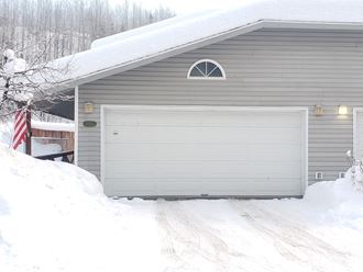 a gray garage with a white door in the snow