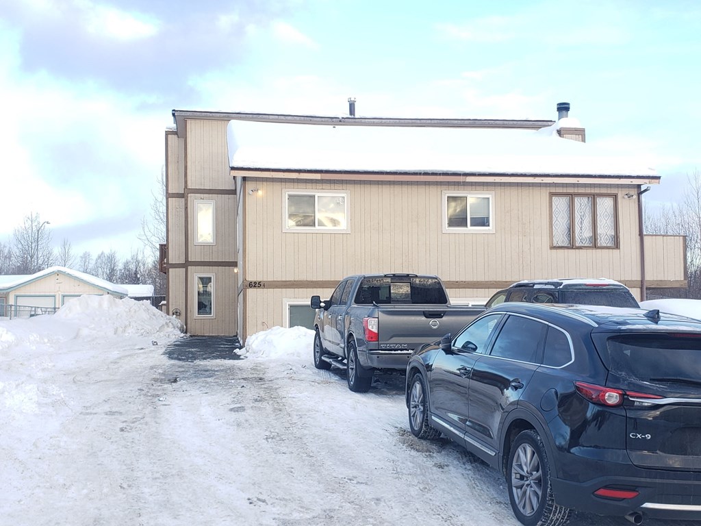 a house with cars parked in front of it in the snow