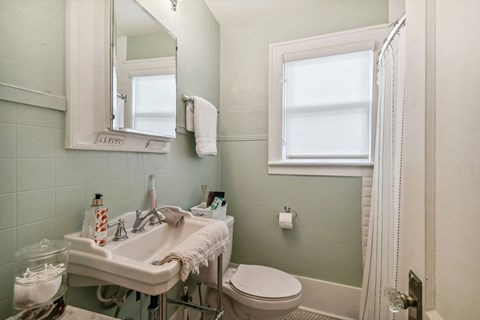 A bathroom with a sink, toilet, and mirror.
